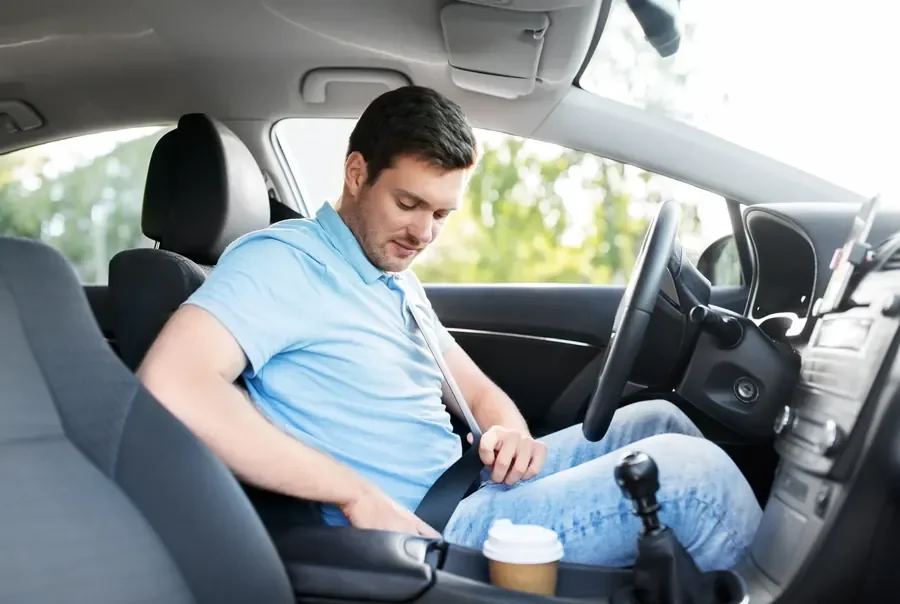 Occupant seated in a passenger car with the seat belt fastened across the chest and lap