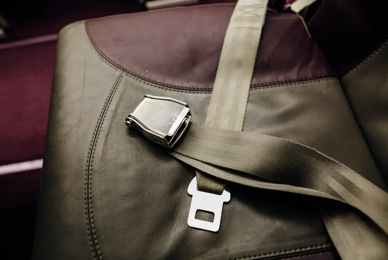 Two-point lap seat belt with a metal lift-lever buckle fitted across a bench seat