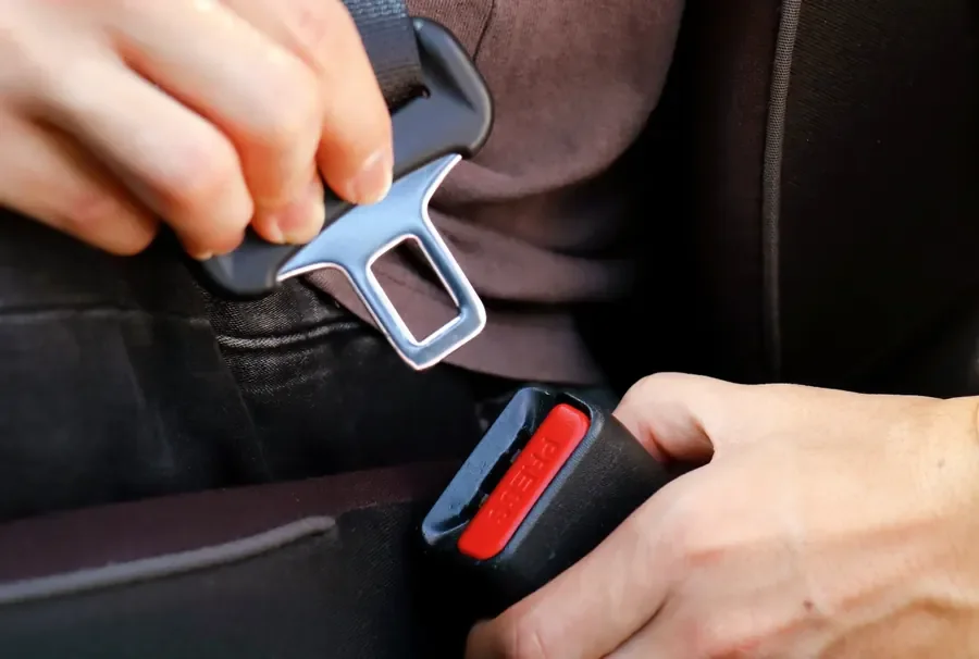 Hands engaging a seat belt latch plate into the buckle receiver during a fitment check
